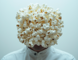 SkinnyPop popcorn bag replacing person's head in surreal image